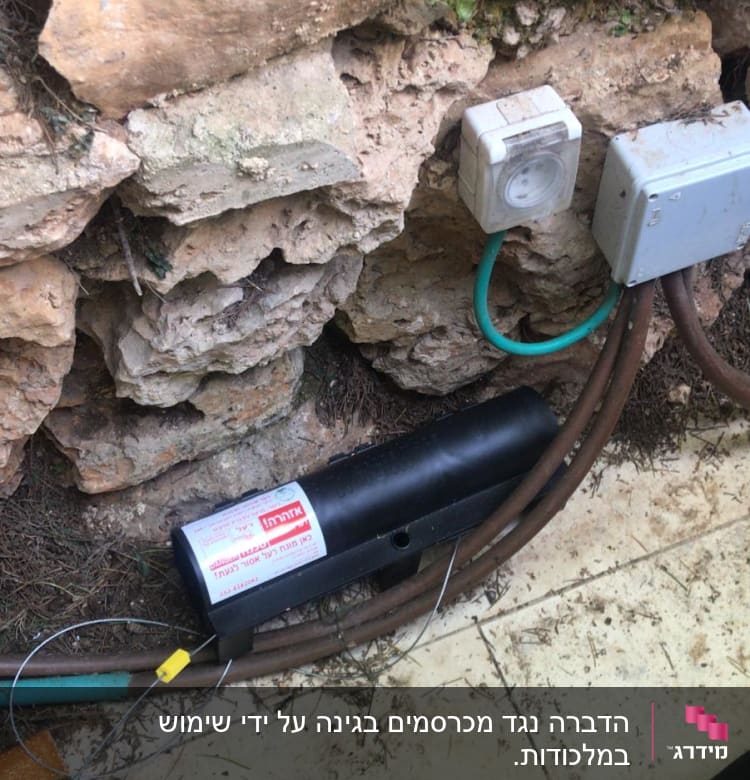 מלכודת מזיקים שחורה ליד קיר אבן